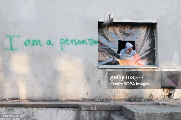 Refugee looks out of the window of former barracks in Belgrade. The barracks were used as shelter by refugees and migrants. Serbia is a country...