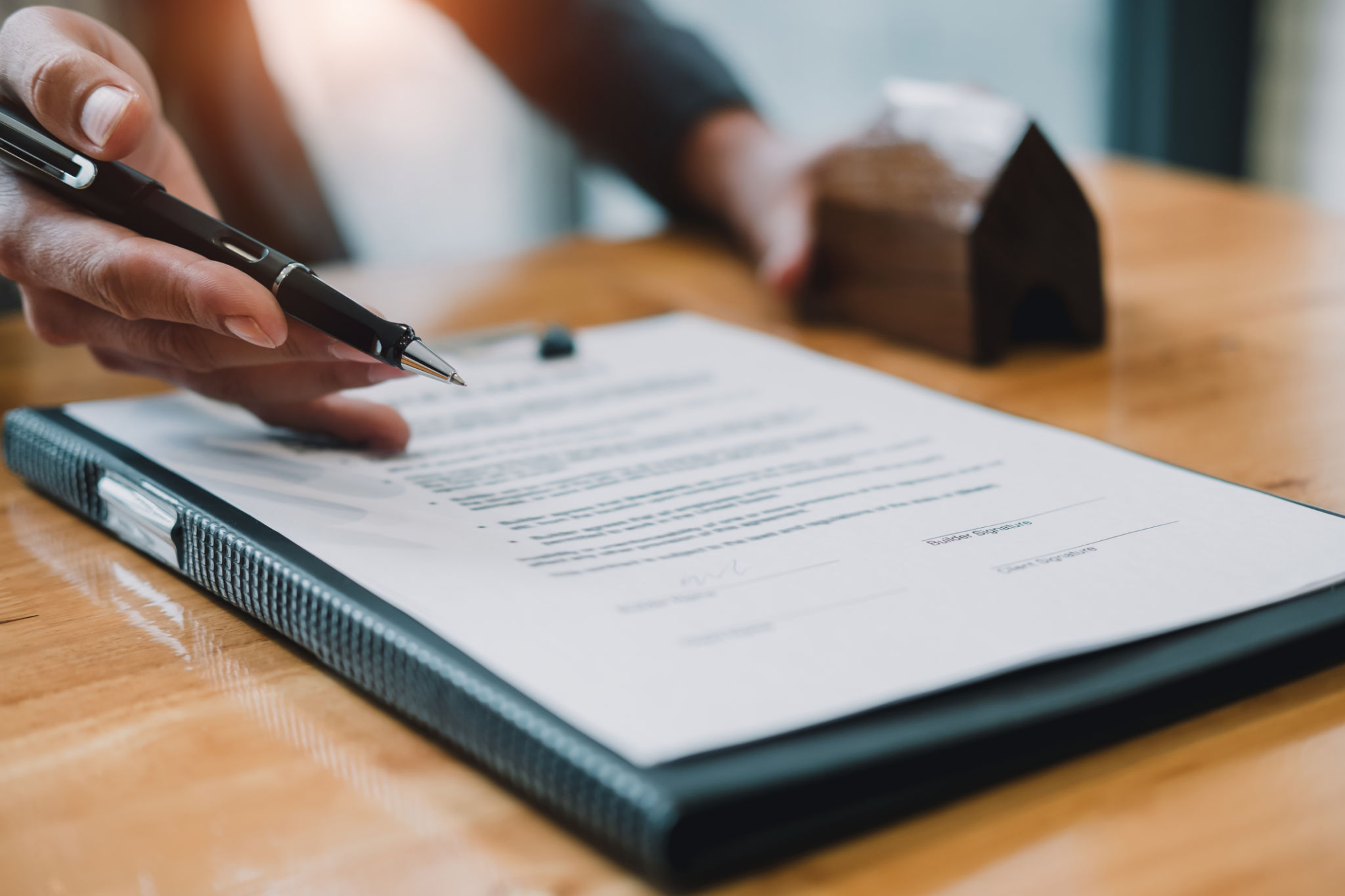 Signing contract. Close-up of confident young man signing some document while another man in shirt and tie sitting close to him and pointing document Signing contract. Close-up of confident young man signing some document while another man in shirt and tie sitting close to him and pointing document