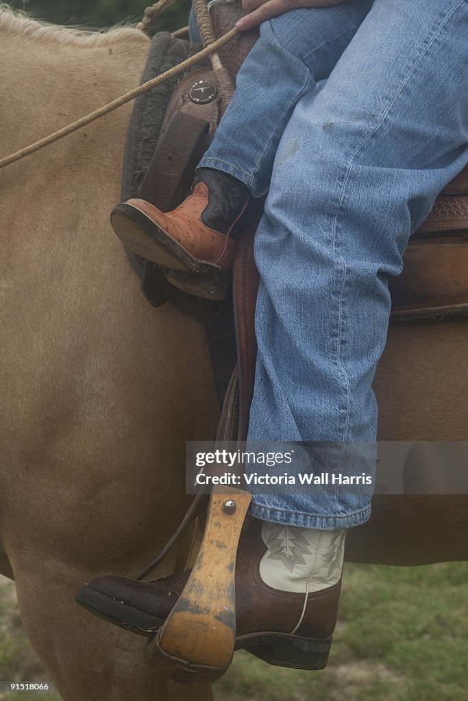 Big and little cowboy boots on horse in stirrups