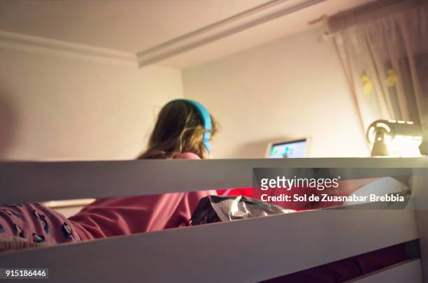 preteen girl listening to music or making a video conference with a friend in her bedroom - bunk bed stockfoto's en -beelden