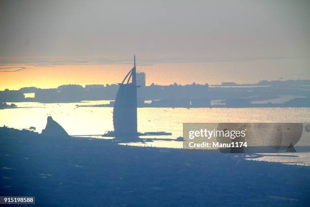 dubai skyline view to burj al arab hotel over the horizon. - burj al arab night stock pictures, royalty-free photos & images