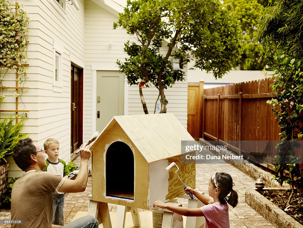 Father and children work on dog house.