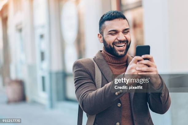 lächelnder mann mit ihrem smartphone im freien in der stadt - vorderasiatische abstammung stock-fotos und bilder