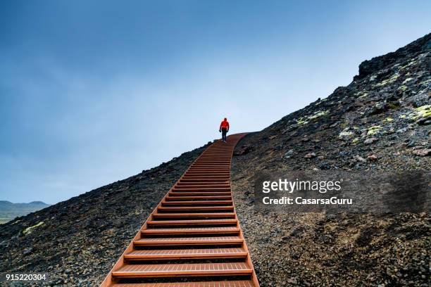hombre caminando sobre los escalones en una montaña contra el cielo azul - subir fotografías e imágenes de stock