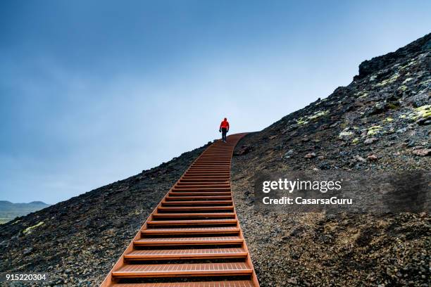 homme qui marche sur l’escalier sur une montagne contre le ciel bleu - escalier photos et images de collection