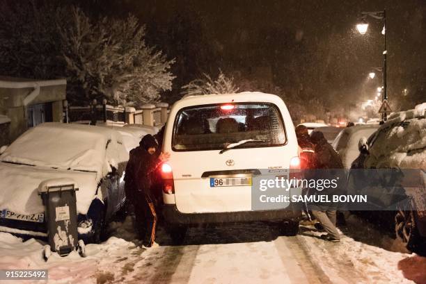 People stand next to stranded vehicles blocked on the D444 road near Bievres, southwest of Paris, early on February 7 after heavy overnight snowfall...