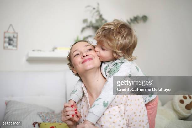 a little boy taking his mum in his arms in the bedroom - affettuoso foto e immagini stock