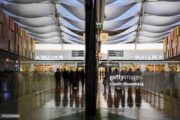 Visitors walk past retail stores in a shopping arcade at the Dolce Vita Tejo shopping mall, operated by AXA Real Estate Investment Managers SGR SpA,...