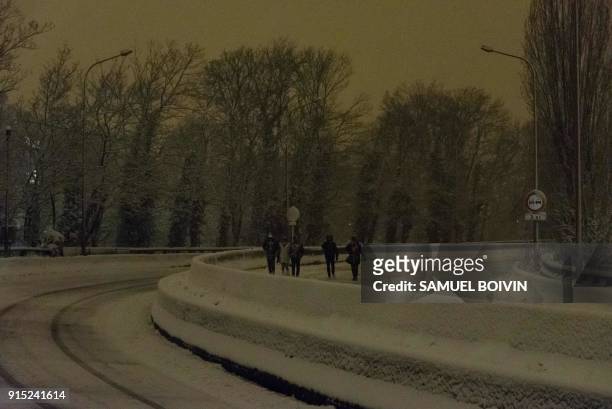 People walk on the deserted and snow-covered N118 main road near Velizy-Villacoublay overnight on February 6, 2018 after its closure following heavy...