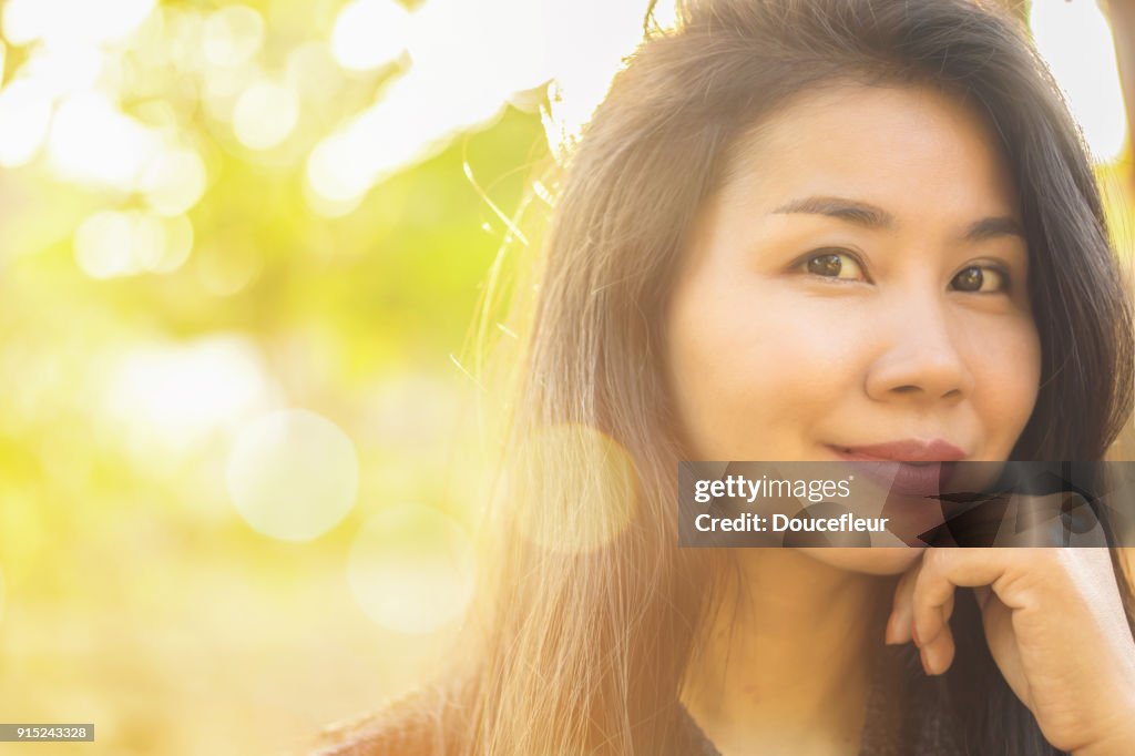Beautiful young Asian woman smiling at the camera with nature background