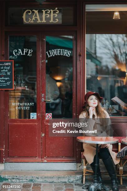 young fashionable woman sits outside a cafe along the streets of paris - french women stock pictures, royalty-free photos & images