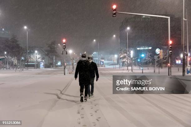 People who were stranded by the snow and left their vehicle at the entrance of the city, walk on the snow-covered street and search for an emergency...