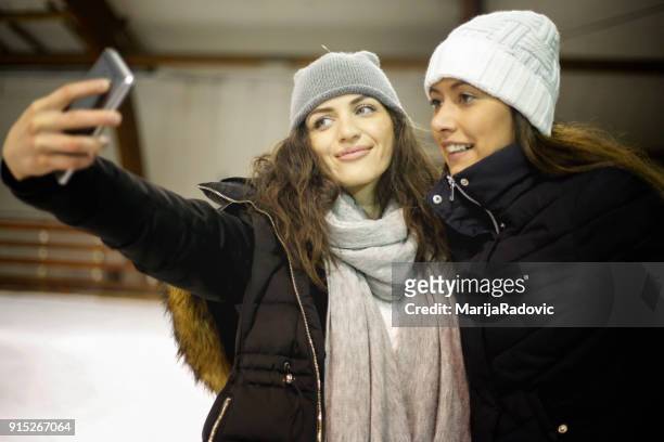 due belle ragazze che indossano caldi vestiti invernali pattinaggio su ghiaccio - capelli ghiaccio foto e immagini stock