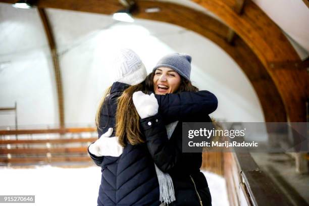 due belle ragazze che indossano caldi vestiti invernali pattinaggio su ghiaccio - capelli ghiaccio foto e immagini stock