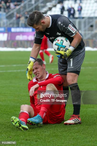 Stanislav Iljutcenko of Duisburg on the ground and Goalkeeper Daniel Heuer Fernandes of Darmstadt helps him during the Second Bundesliga match...