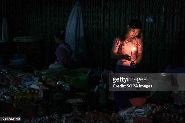 Woman holds a candle in a night market in central Yangon.
