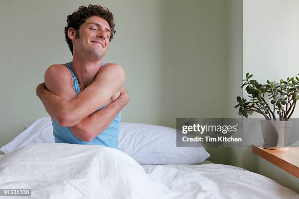 man in bed, waking up, hugging himself - krama sig själv bildbanksfoton och bilder
