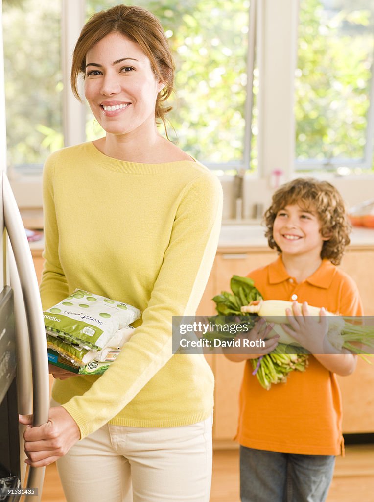 Mom putting away groceries with kids