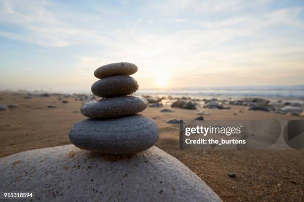 stack of balanced stones at beach during sunset - balanced rocks stock pictures, royalty-free photos & images