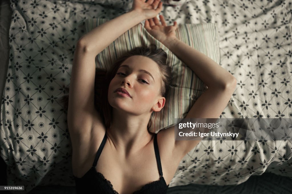 Young woman stretching in bed after waking up