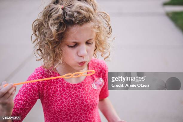 little girl blowing bubbles through bubble wand - annie otzen stock pictures, royalty-free photos & images