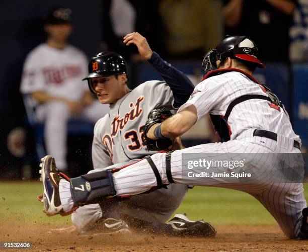 Don Kelly of the Detroit Tigers slides safely into home plate to score as Joe Mauer of the Minnesota Twins applies the tag during the 10th inning of...
