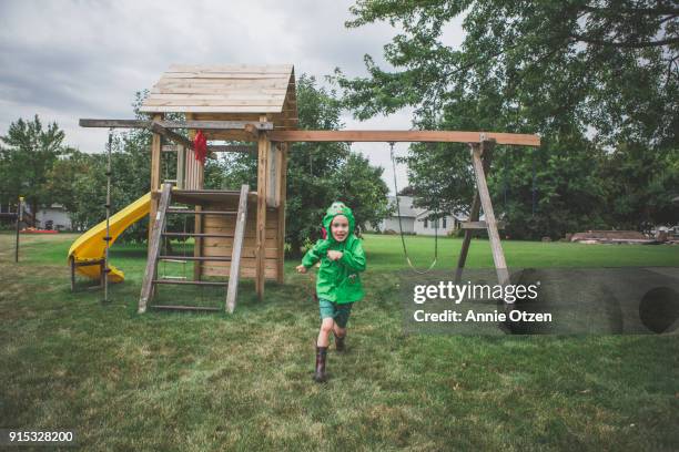 boy in raincoat running - schaukel regen stock-fotos und bilder