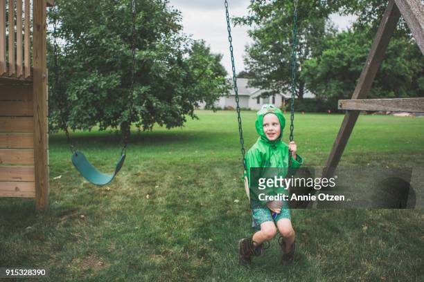 boy sitting on swing set swing - wellington boots stock pictures, royalty-free photos & images