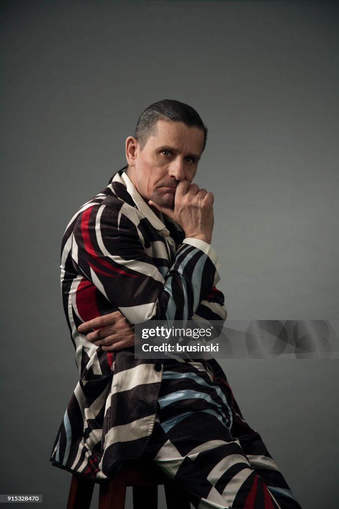 Portrait of a bizarre man in a suit in a studio on a gray background