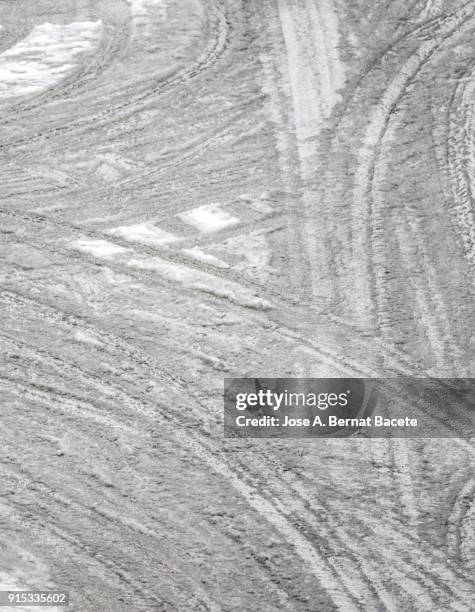 full frame high sight of the street of a covered city of snow with the tracks of the of tire of cars and vehicles.  spain - snow melting on car stock pictures, royalty-free photos & images