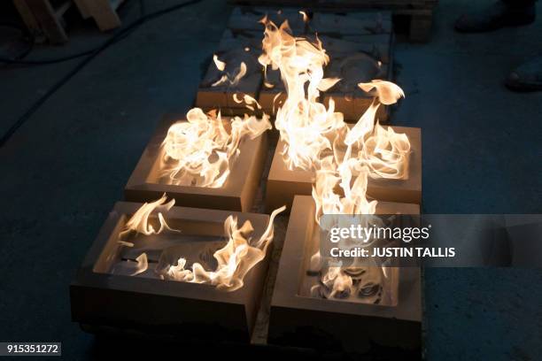 Mask moulds are set alight to burn off any impurities before casting, during a photo call at the New Pro Foundries, west of London, on February 7,...