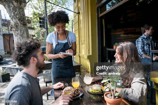 gelukkige paar genieten van lunch op een mooie dag en iets aan de serveerster te bestellen - ober stockfoto's en -beelden