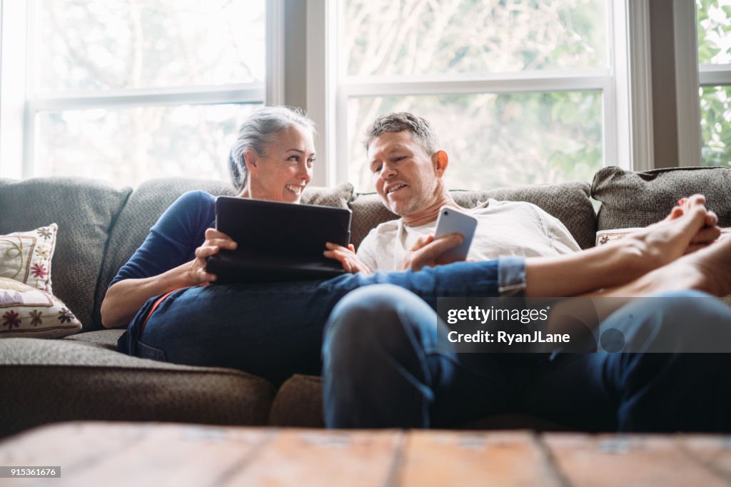 Madura pareja relajante con Tablet y Smartphone