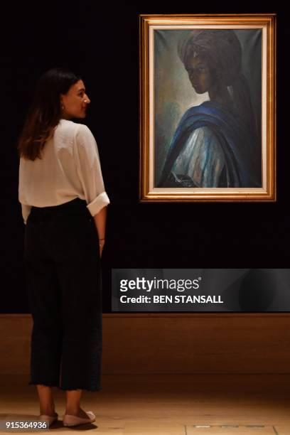 An employee poses with a work of art by Nigerian painter and sculptor Ben Enwonwu entitled 'Tutu' expected to realise 200,000-300,000 GBP at auction...