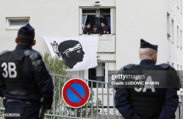Riot policemen watch as residents display a Corsican flag in the window of a building near the Alb'Oru cultural centre, where the French President...