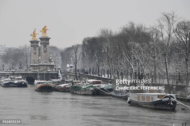 Snow coverd houseboats are moored on the banks of the River Seine near the Alexandre III bridge in Paris on February 7 following heavy snowfall....
