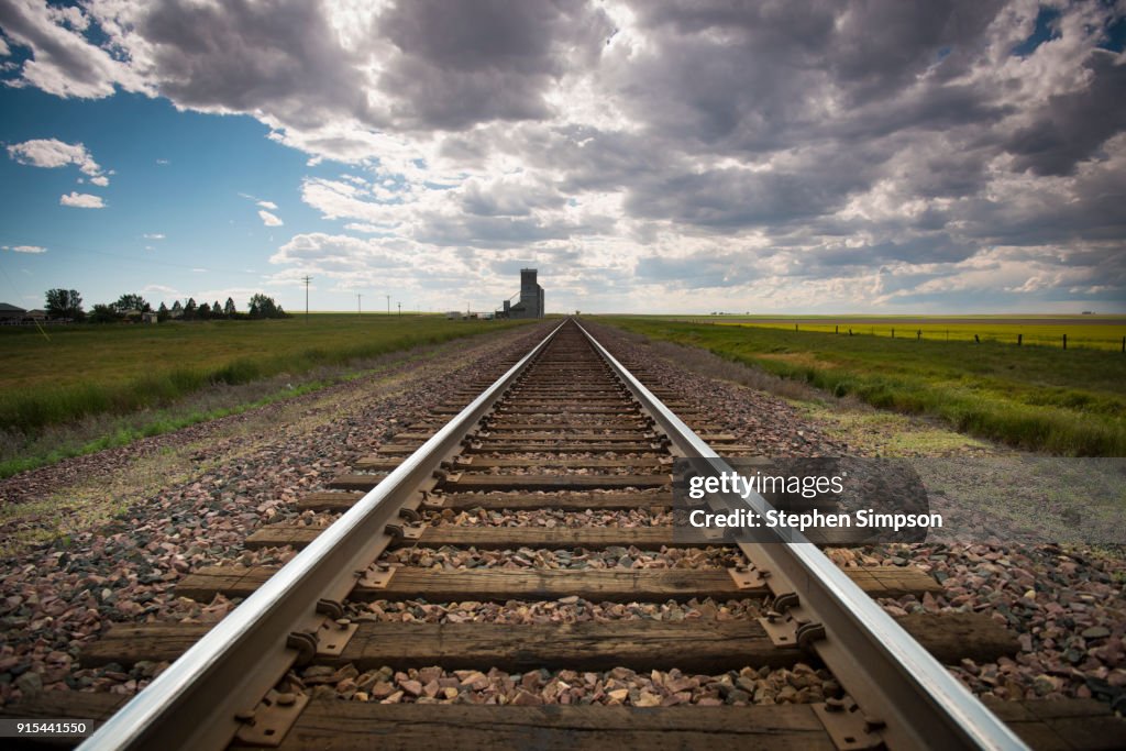 Railroad tracks recede to the horizon, dark summer sky approaching
