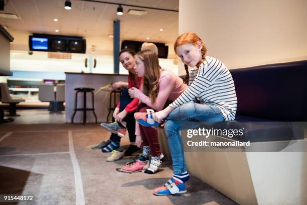 vrienden en familie op tien pin bowling en bowlingschoenen zetten - ten pin bowling stockfoto's en -beelden