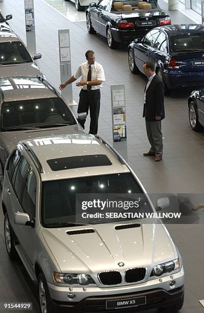 Customer confers with a car dealer next to a BMW X5 car on July 01 at a BMW store in Leipzig. AFP PHOTO/DDP/Jens Schlueter