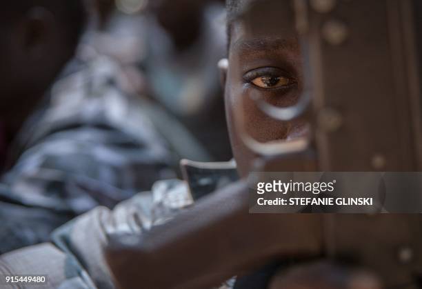 Newly released child soldier looks through a rifle trigger guard during a release ceremony for child soldiers in Yambio, South Sudan, on February 7,...