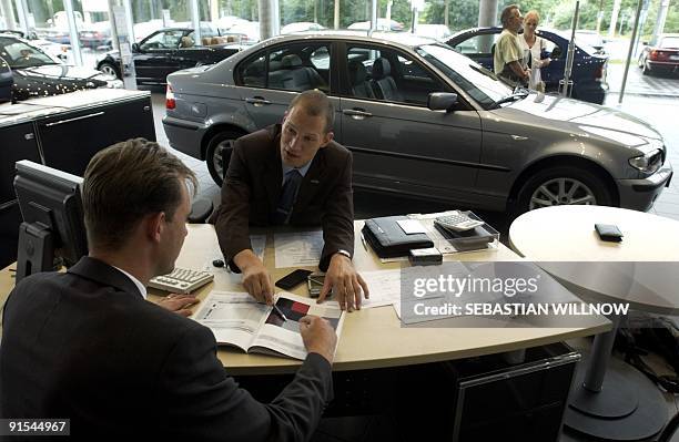 Customer confers with a car dealer next to a BMW X5 car on July 01 at a BMW store in Leipzig. AFP PHOTO/DDP/Jens Schlueter