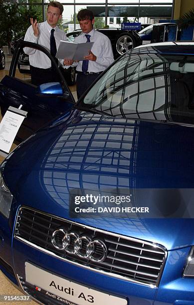 Salesmen examine an Audi A3 limousine on June 06, 2003 in an Audi store in Dresden. AFP PHOTO/DDP-Robert Michael