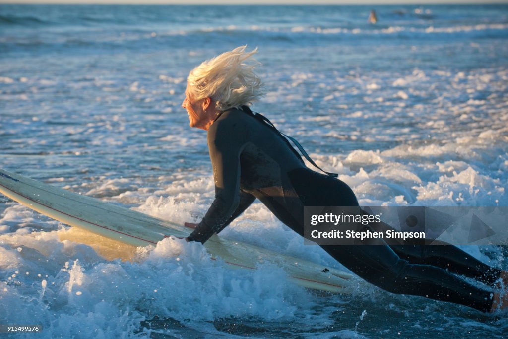 Fit mature female surfer on surfboard on wave