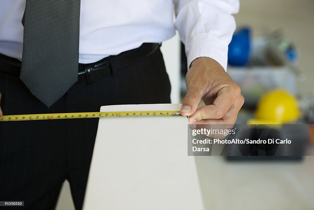 Well-dressed person measuring ledge width, close-up