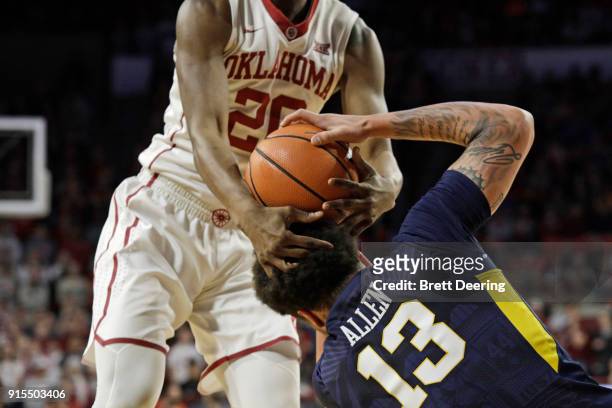 Kameron McGusty of the Oklahoma Sooners and Teddy Allen of the West Virginia Mountaineers struggle for the ball at Lloyd Noble Center on February 5,...