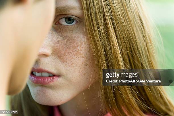 young woman facing man, staring warily at camera, cropped - suspicion stock-fotos und bilder