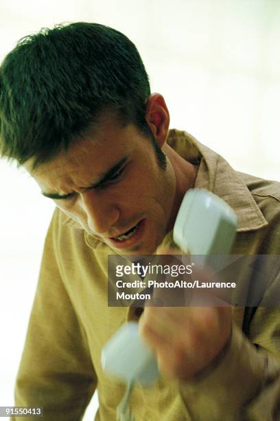 man gripping phone receiver, furrowing brow - knitting brow stock pictures, royalty-free photos & images