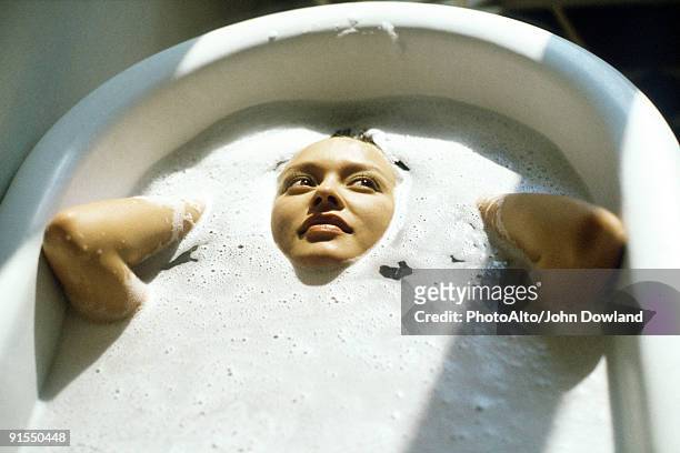 woman soaking in bathtub - schaumbad stock-fotos und bilder
