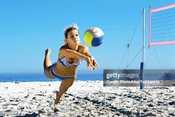 female playing beach volleyball diving to catch ball - volear fotografías e imágenes de stock