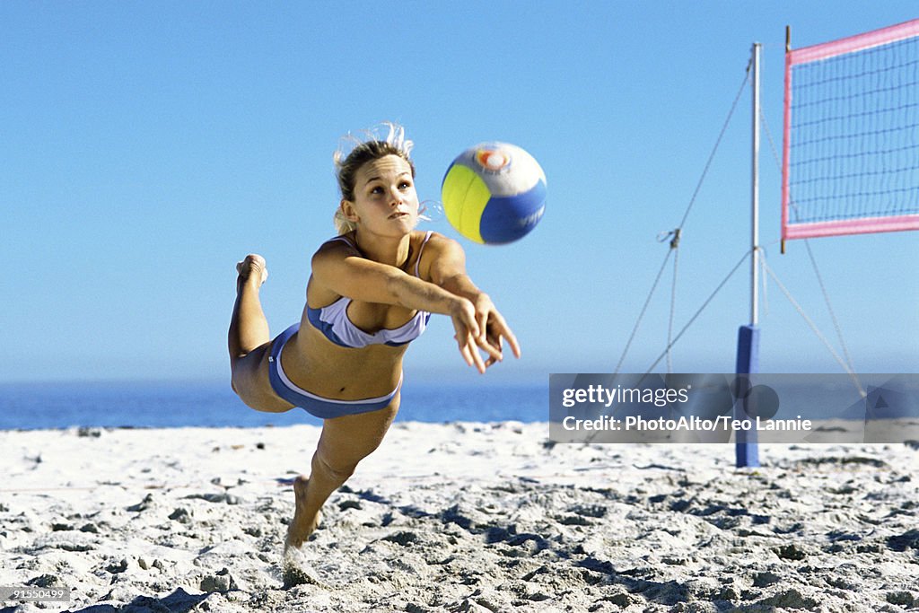 Female playing beach volleyball diving to catch ball